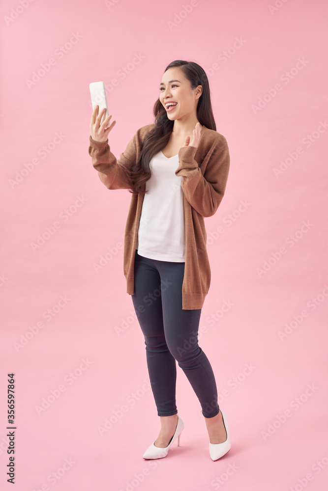 年轻美女在粉色背景下使用手机工作室