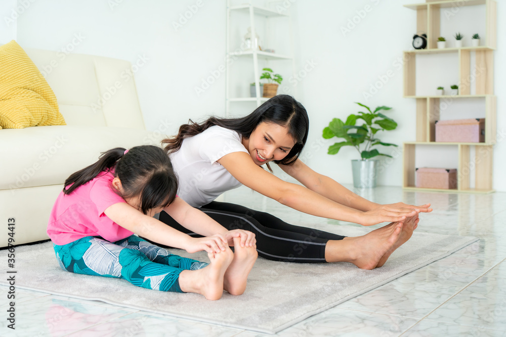 亚洲母亲和女儿在家里的客厅里做健身运动，以保持身体和我的健康