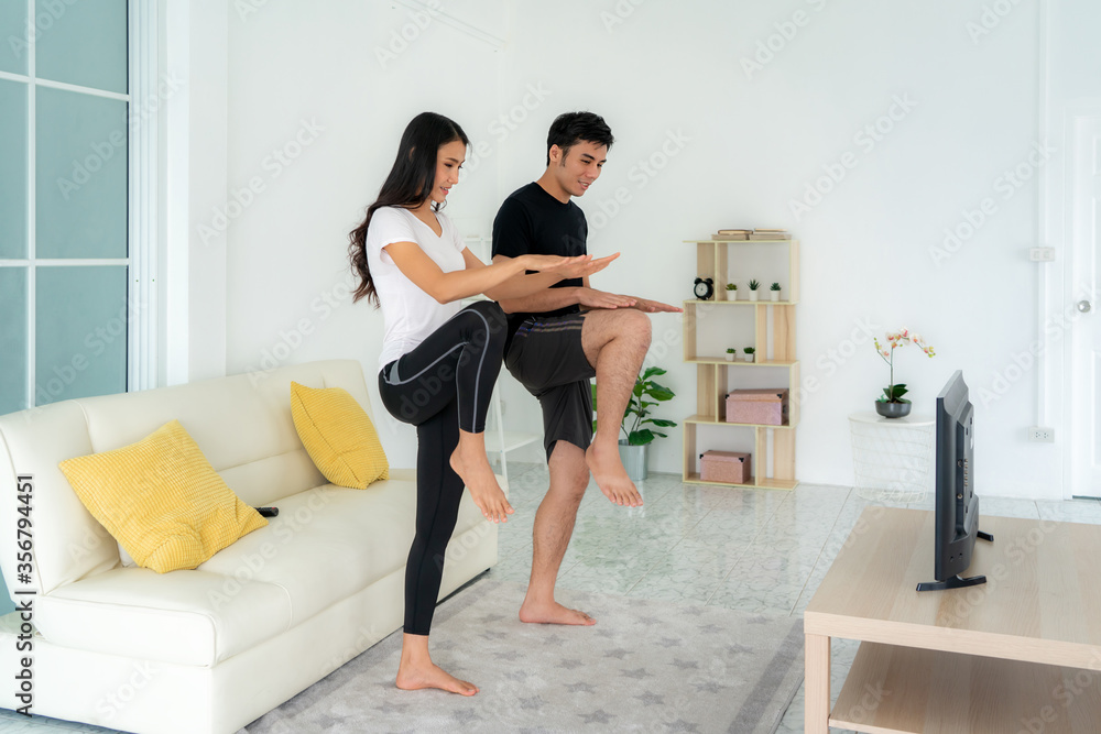 年轻的亚洲夫妇一起进行高强度间歇训练，在家看电视，男人和女人