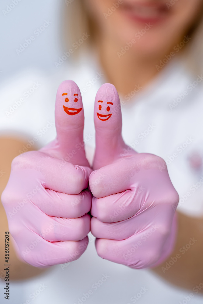 手戴粉色手套在镜头前。展示酷炫的标志。拇指上画着红色的微笑。