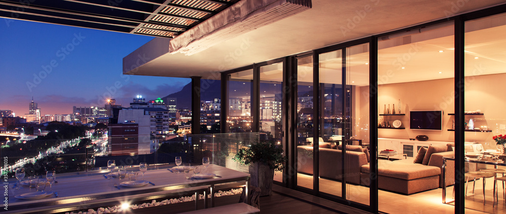 Illuminated modern living room and patio overlooking city