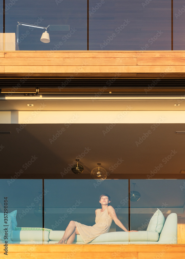 Woman sitting on sunny luxury balcony