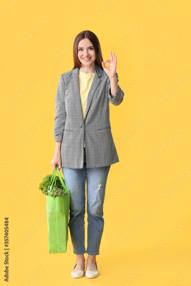 包里有食物的年轻女子在彩色背景上显示OK手势