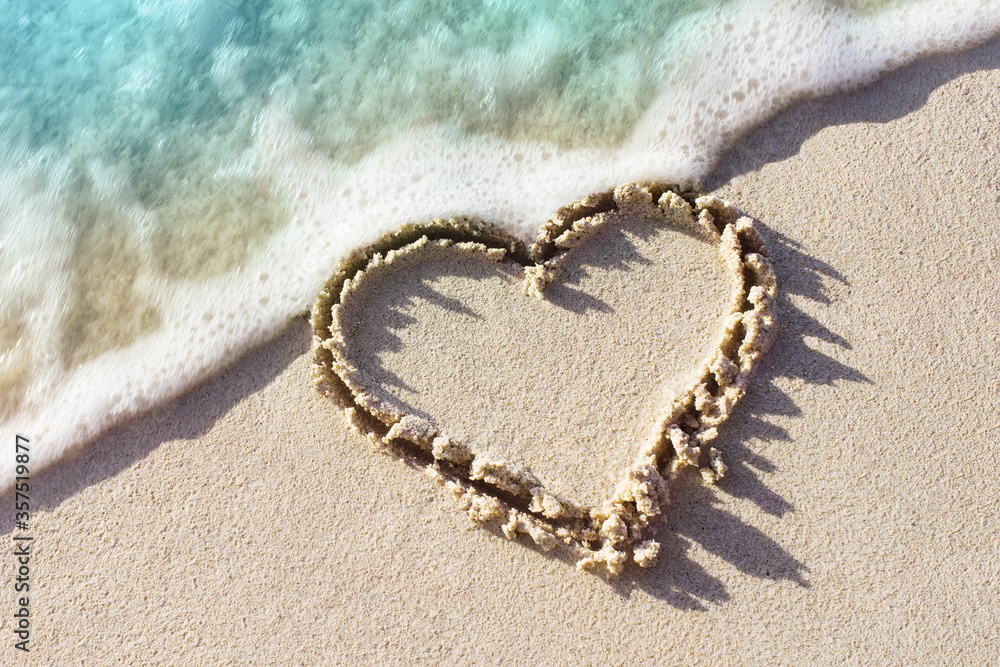 海浪拍岸沙滩上手写的心形符号