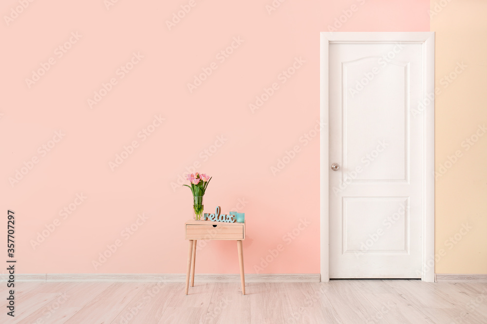 房间彩色墙附近有鲜花的桌子