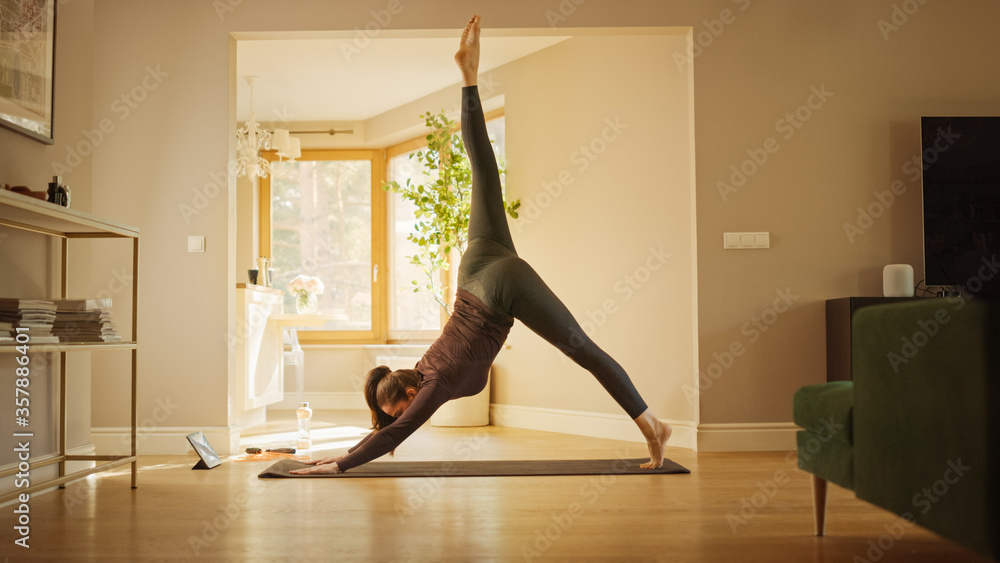 Strong Fitness Girl in Workout Clothes Does Stretching Yoga Exercises at Home, Uses Digital Tablet f