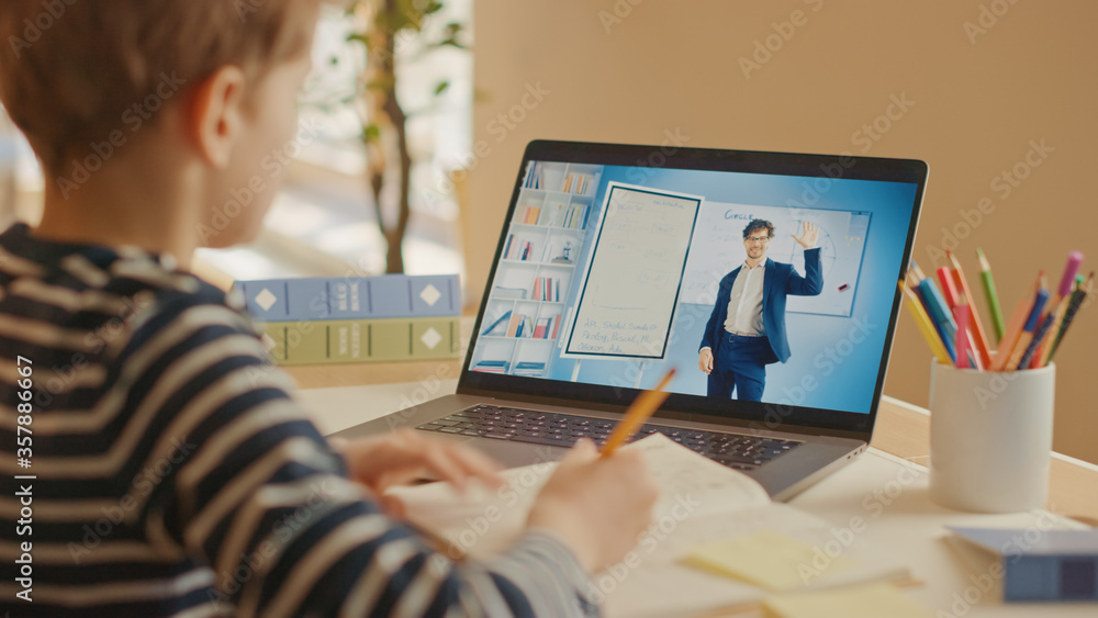 聪明的小男孩用笔记本电脑与老师视频通话。屏幕显示在线教学讲座