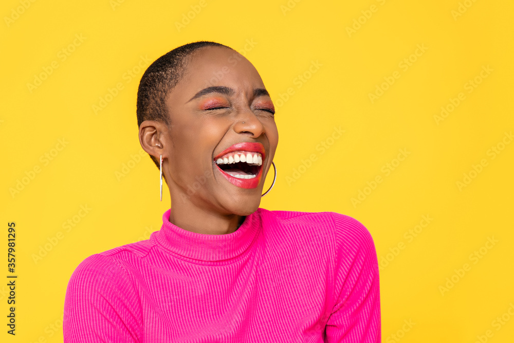 快乐乐观的非裔美国妇女，穿着五颜六色的粉红色衣服，在黄色的背上独自大笑