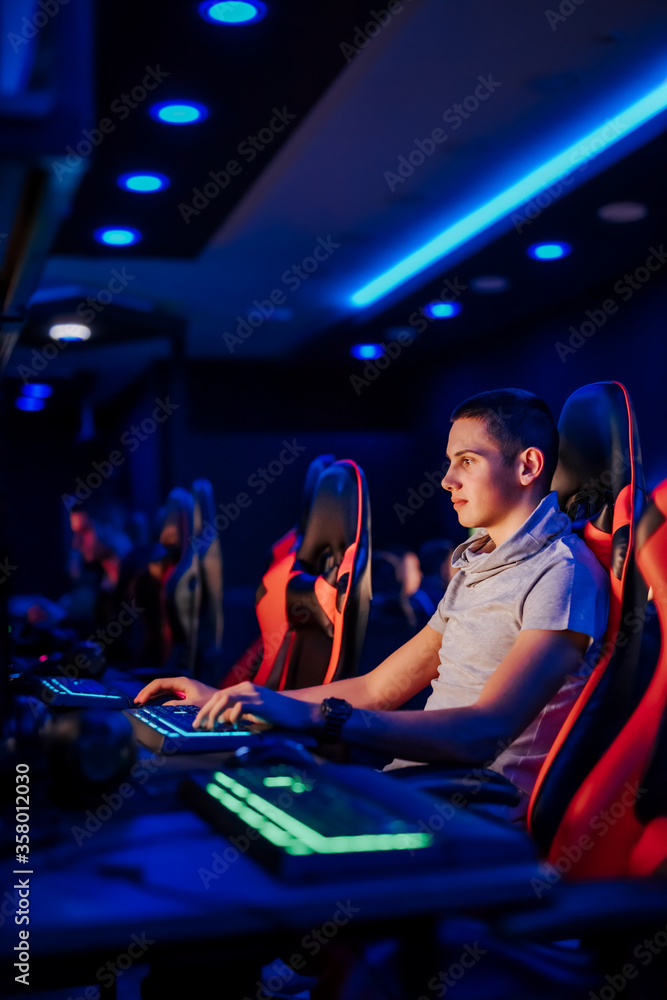 Playing online video game. Portrait of a young gamer at internet cafe or playroom.