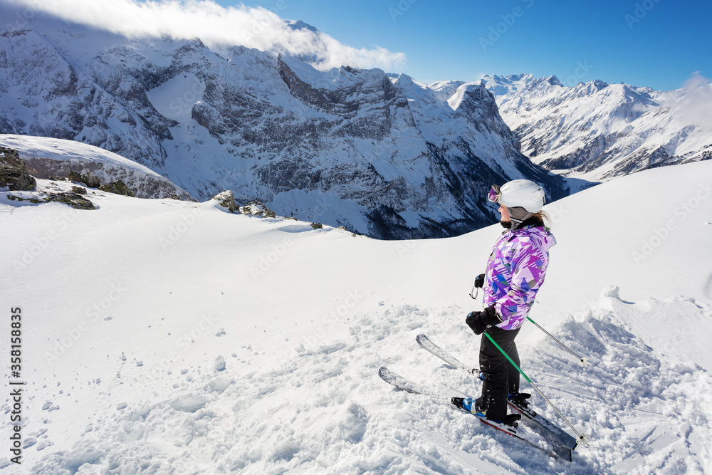 十几岁的女孩穿着滑雪服站在山顶上俯瞰山谷