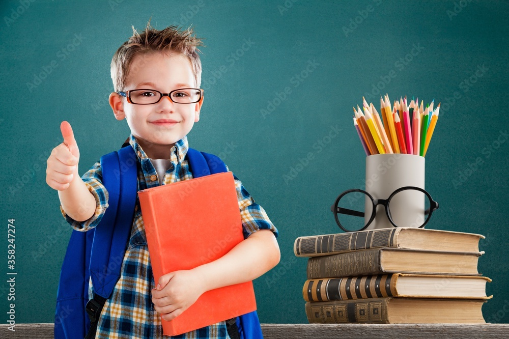 Stack of vintage books and colorful pencils on the desk and child