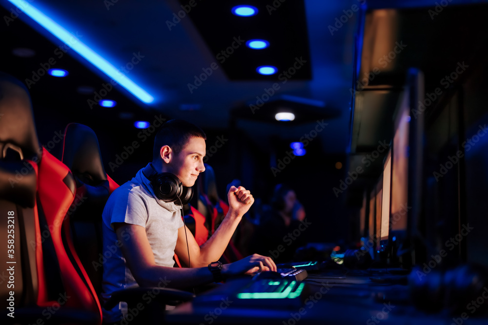 快乐的年轻玩家在网吧玩在线视频游戏时做手势，肖像，侧视图。