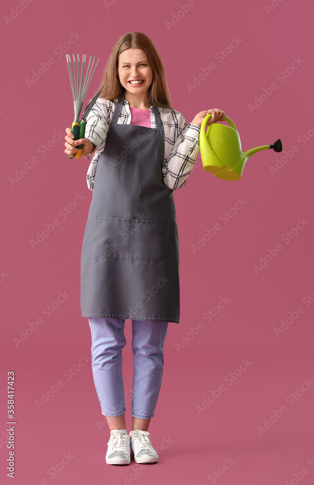 年轻女子拿着水罐和彩色背景的园艺工具