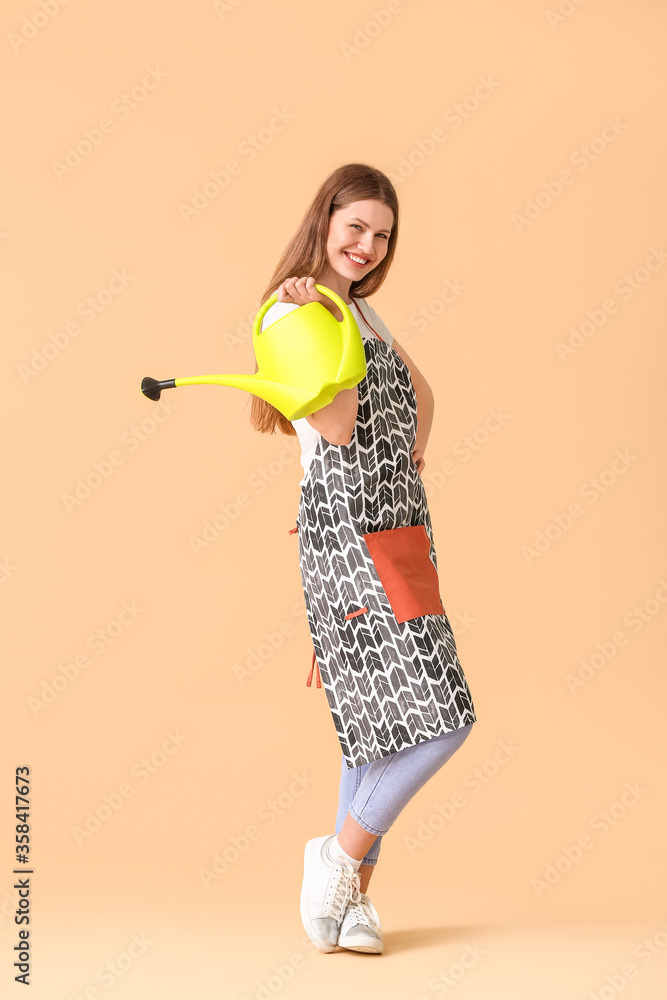 Young woman with watering can on color background