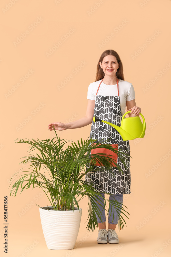 年轻女性，带着喷壶和彩色背景的室内植物