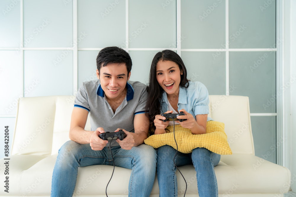 亚洲情侣男女坐在客厅沙发上玩游戏杆