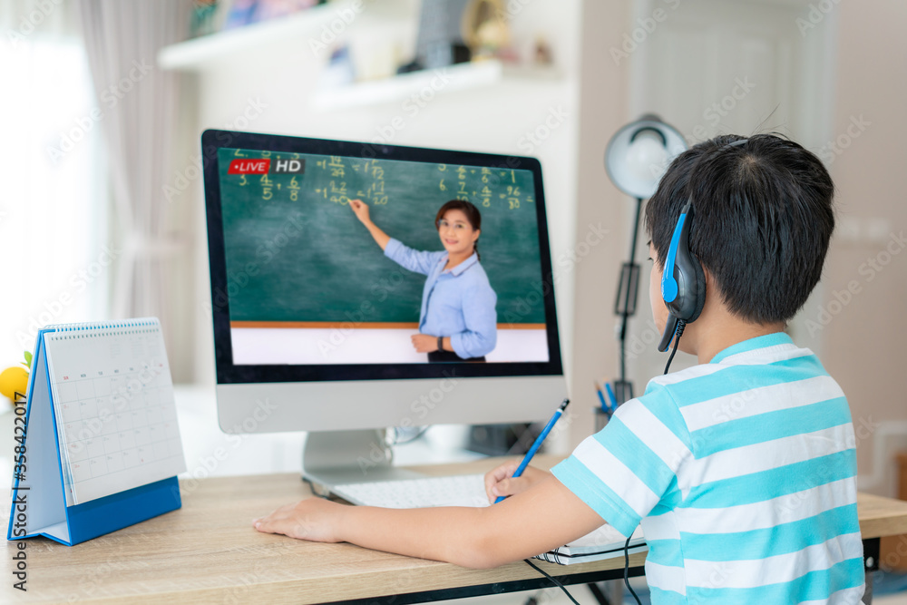 亚洲学生男孩与老师在家客厅的电脑上进行视频会议电子学习。e-le