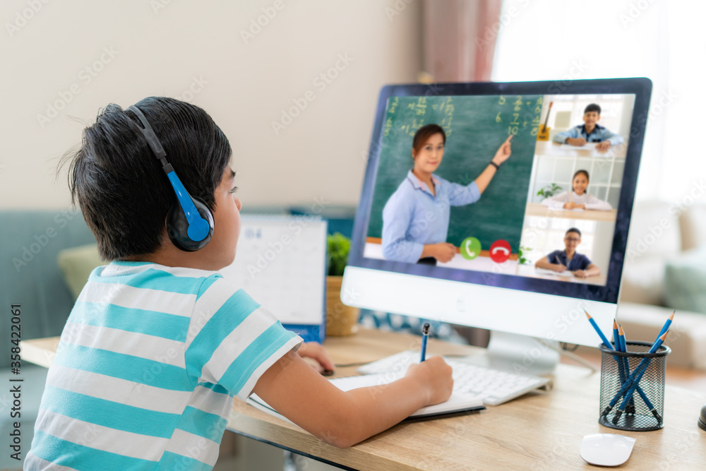 亚洲男生与老师和同学在客厅的电脑上进行视频会议电子学习