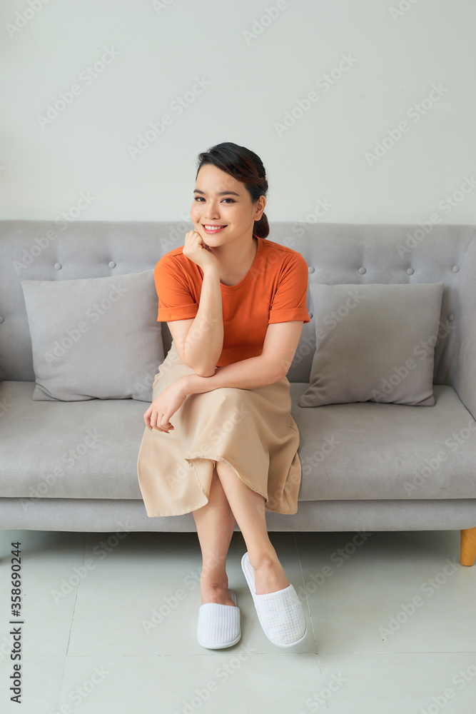 Beautiful young woman sitting on sofa, indoors