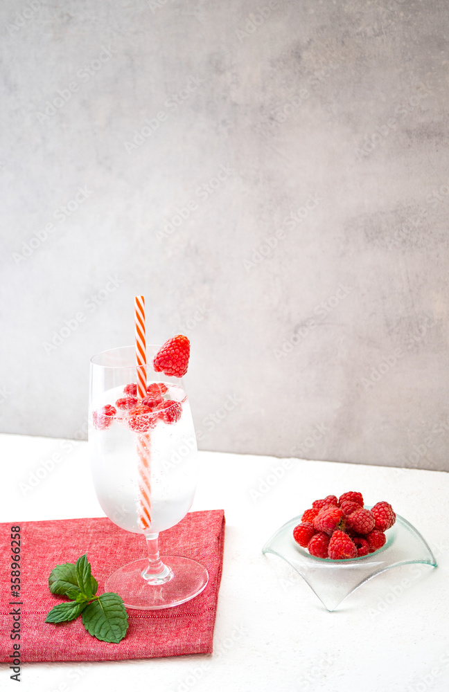 用鸡尾酒吸管装在杯子里的清爽树莓柠檬水放在红色餐巾和白色标签上