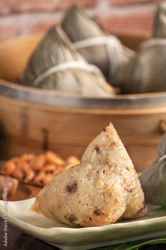 粽子——红砖墙木桌上的蒸笼中的中国粽子食品，靠窗