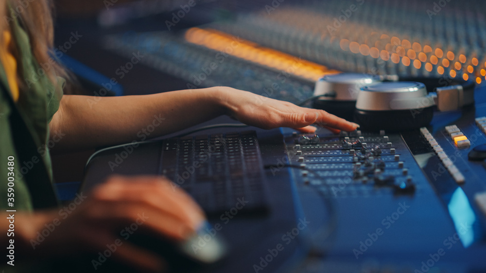 音频工程师、音乐家、艺术家在录音室工作，控制台混音器。女性手