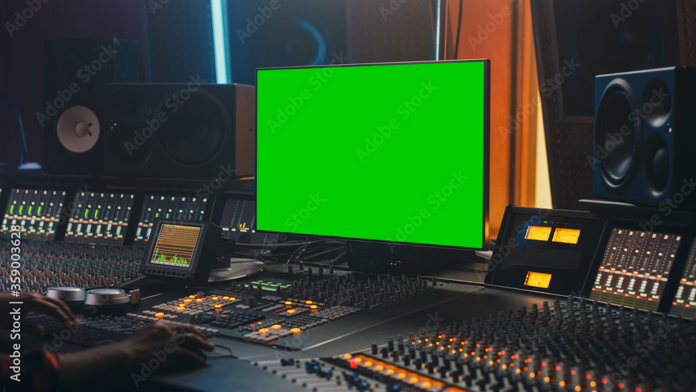 在音乐唱片工作室工作的时尚音频工程师的肖像，使用绿屏电脑，混音器