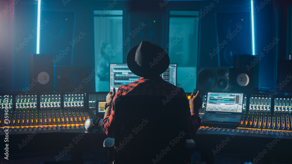 制作人、音频工程师使用控制台在音乐录制工作室录制新专辑曲目，in
