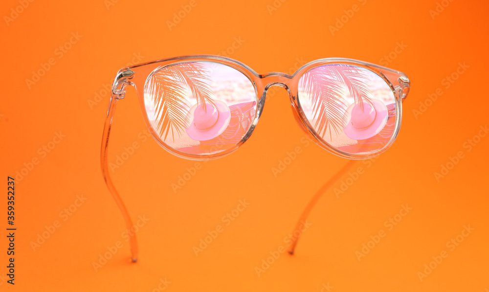 Reflection of beach accessories in sunglasses on color background