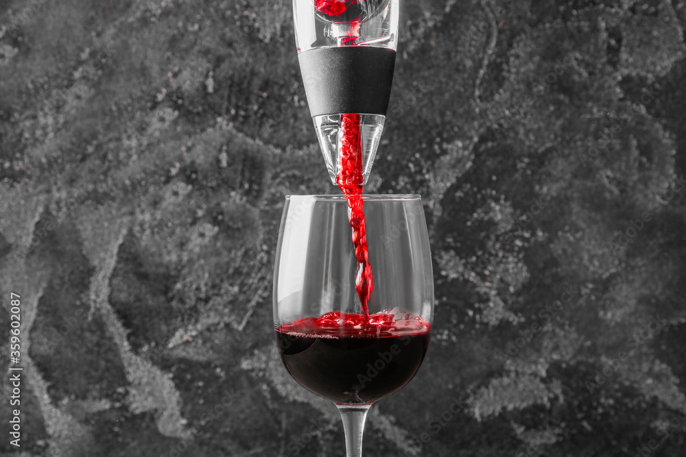 在深色背景下将葡萄酒从曝气器倒入玻璃杯