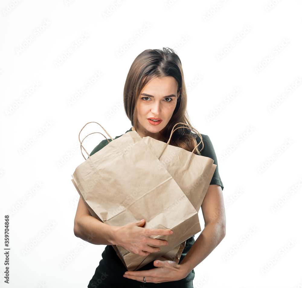 一名女子拿着两个白色背景的杂货购物袋。纸袋靠近面部。背部孤立。