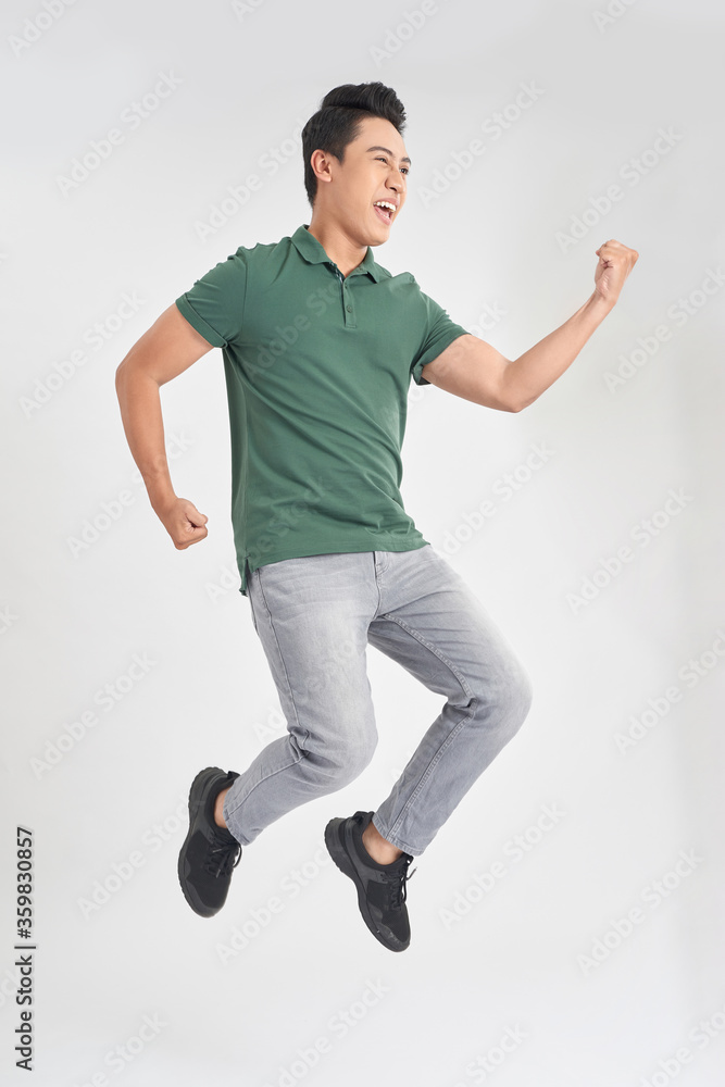 30多岁的滑稽男子穿着休闲t恤和牛仔裤在空气隔离的ov中奔跑或跳跃的全长照片