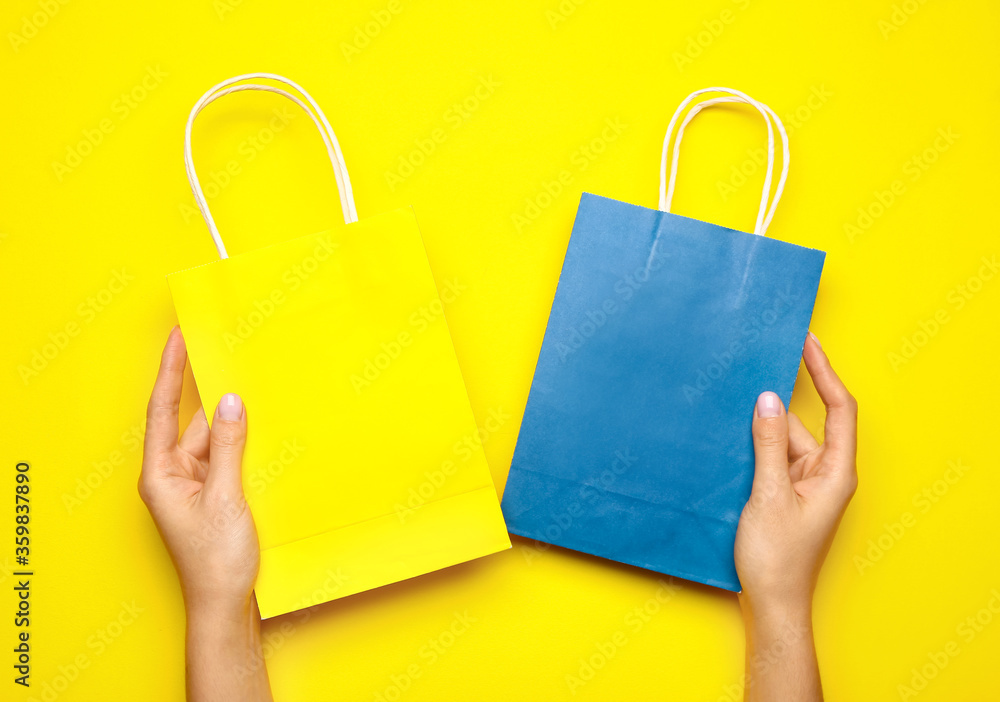 女性手拿彩色背景的纸质购物袋