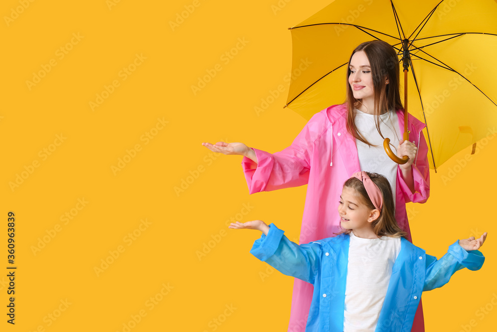 母亲和小女儿带着彩色背景的雨伞
