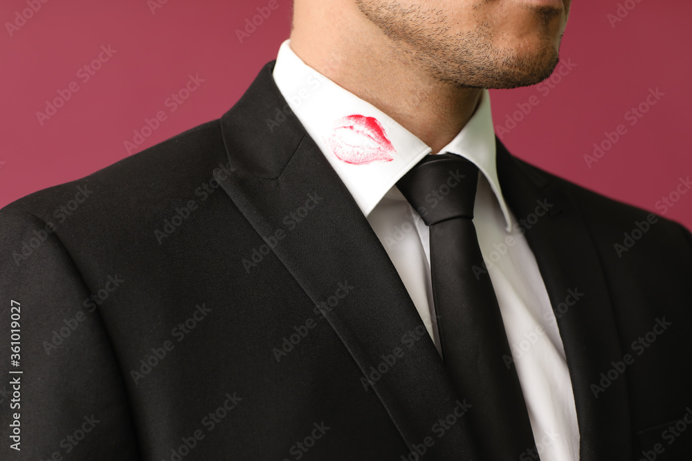 年轻的商人，在彩色背景下，衬衫领子上有嘴唇印花，特写