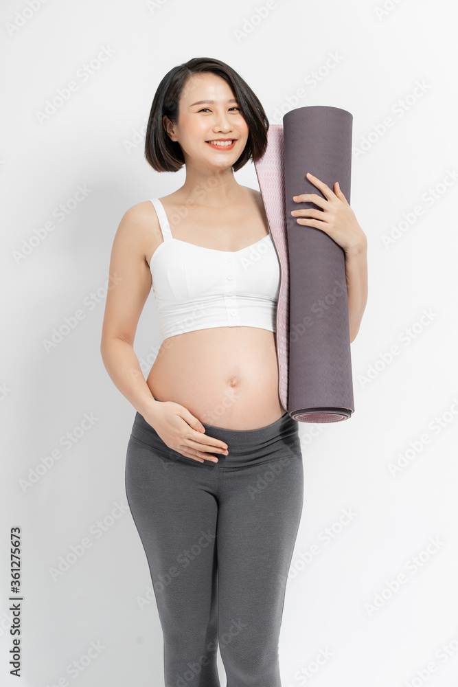 阳性孕妇穿着运动服，手里拿着健身垫。
