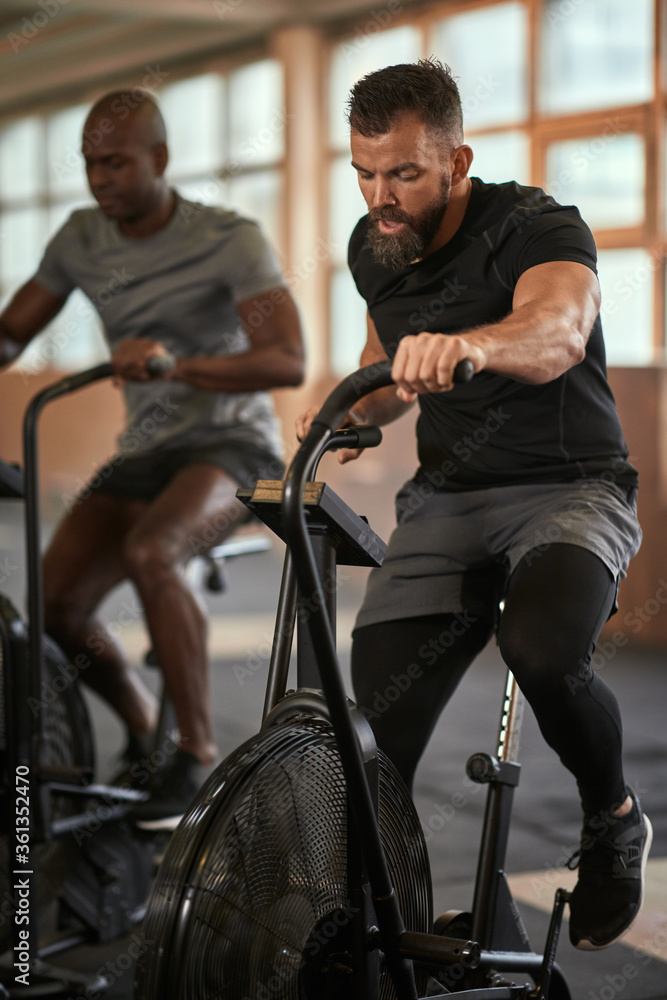 Two men working out on stationary bikes in a gym