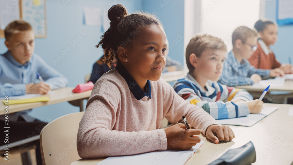 在小学课堂上，聪明的黑人女孩在练习本上写作，参加考试和写作