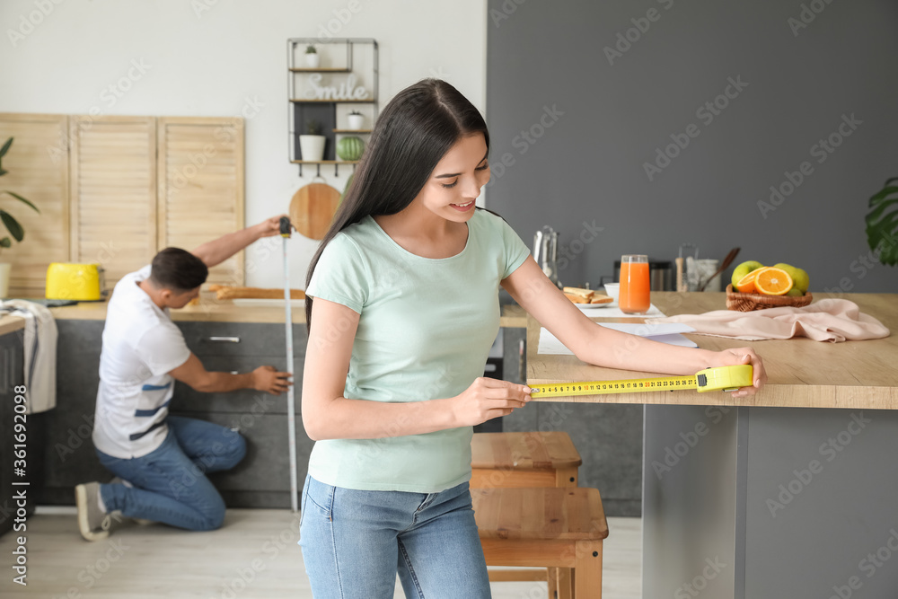 年轻女子在厨房里测量餐桌