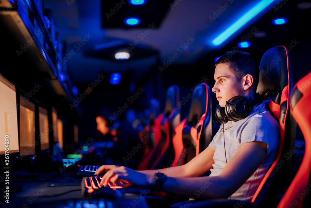 一个专注的玩家在现代网吧使用电脑的特写。
