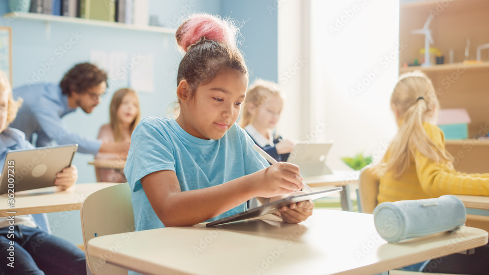 小学计算机科学课：可爱的女孩使用数字平板电脑，她的同学担心