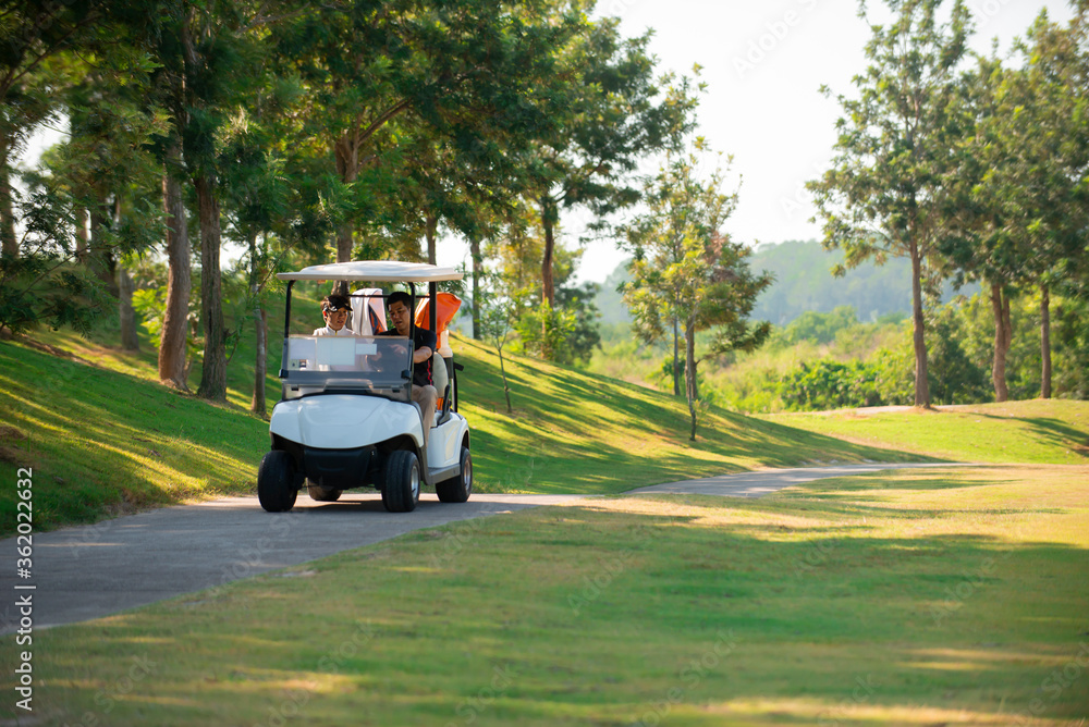 两名亚洲男子高尔夫球手在高尔夫球场驾驶高尔夫球车上路
