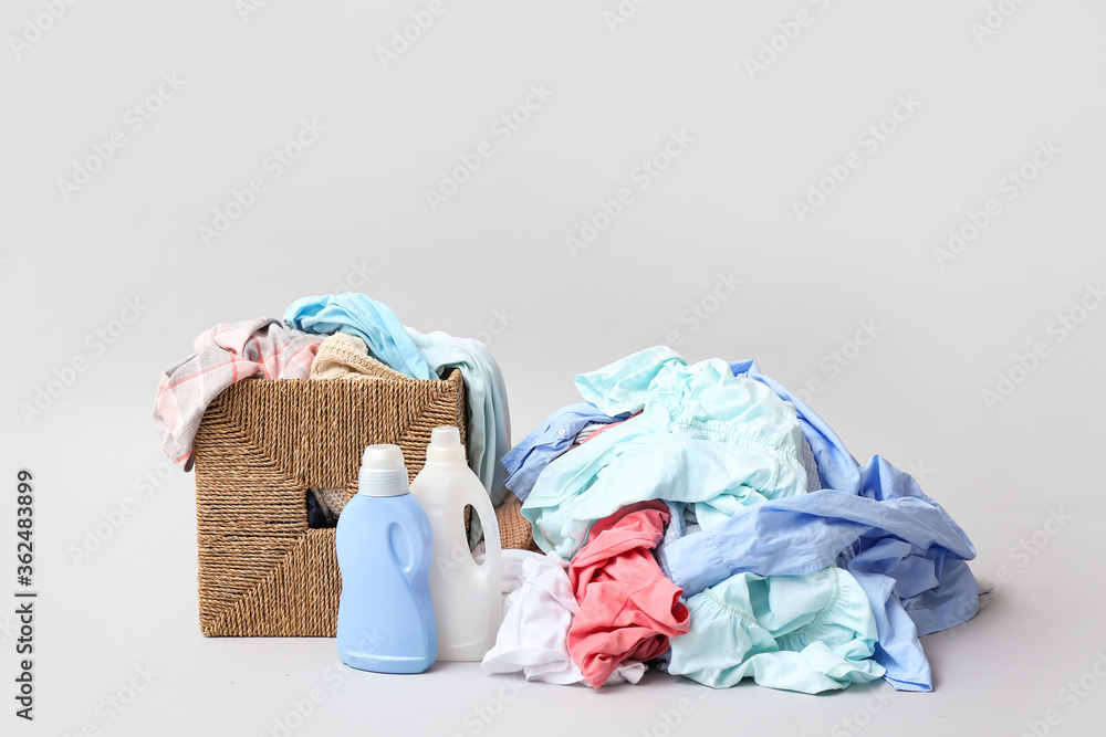 浅色背景下装有脏衣服和洗涤剂的篮子