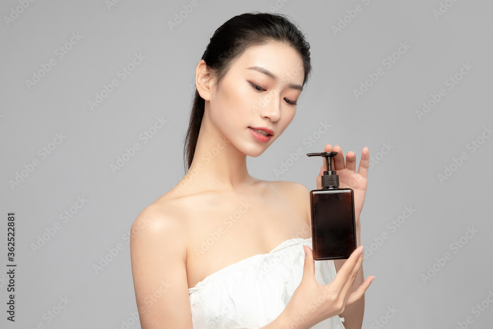 亚洲美女手拿棕色洗发水瓶的面部特写