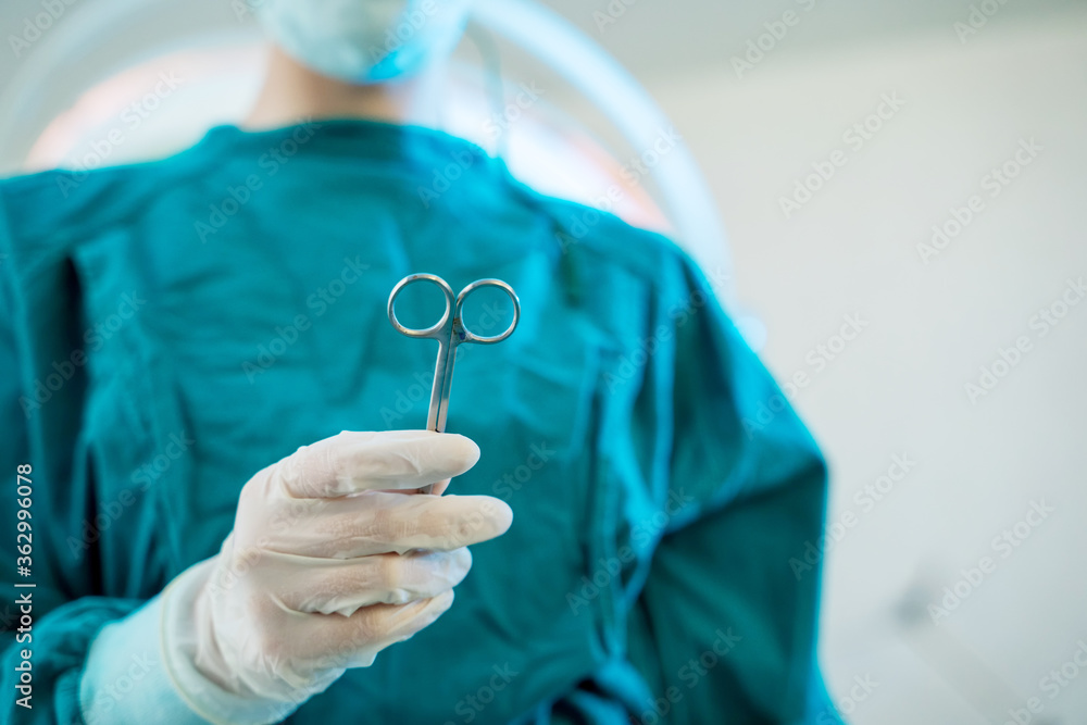 Doctor passing medical tool to surgeon at work in operating room.