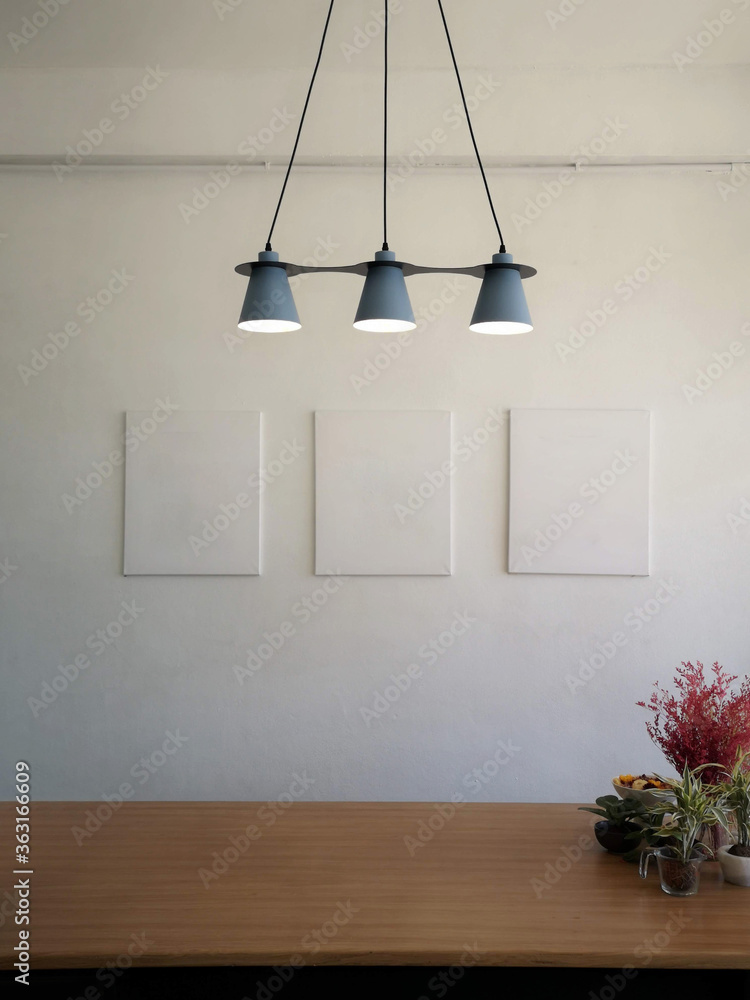 The gray lamp and the white wall have blank picture frames