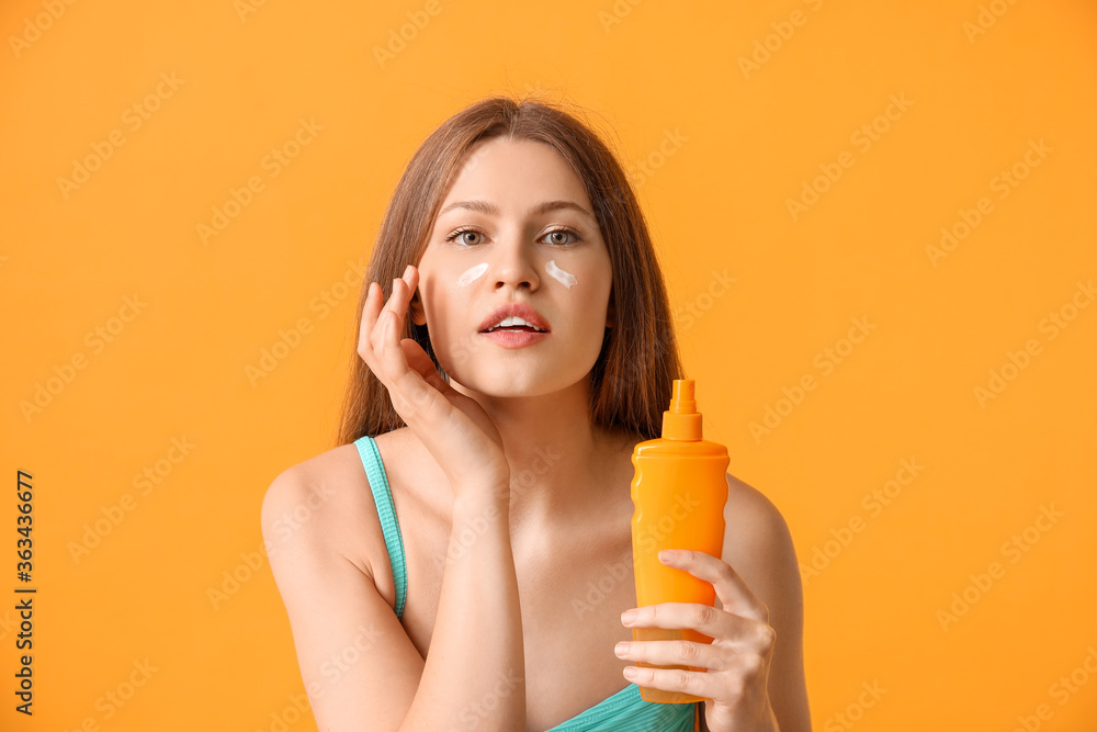 年轻女性在彩色背景下涂抹防晒霜