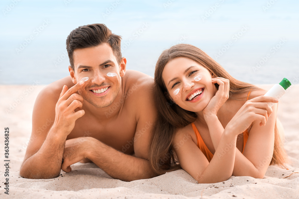 年轻夫妇在海边涂防晒霜