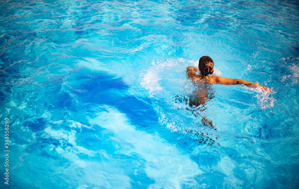 俯视图不明身份的漂亮年轻女孩在下面的水池里快乐地在蓝色清澈的水中戏水