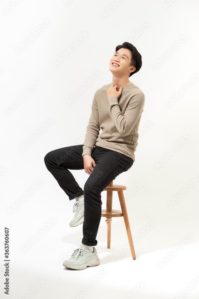 全身亚洲男子坐在白底高脚椅上